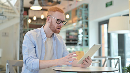 Fototapeta na wymiar Redhead Man Shocked by Loss on Tablet in Cafe