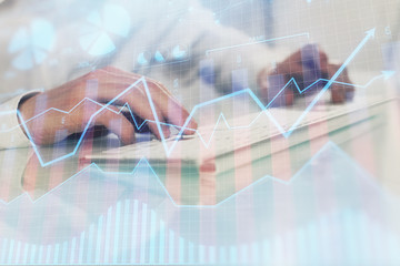 Double exposure of graph with man typing on computer in office on background. Concept of hard work....