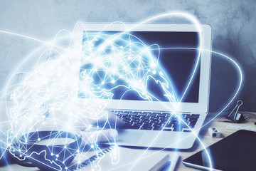 Double exposure of businessman working on laptop on background. International business hologram in front. Concept of success.