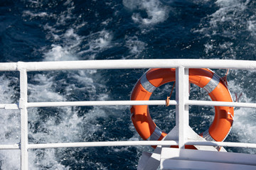Red lifeguard on stern rail boat with swell in the background