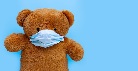 Teddy bear with mask on blue background.