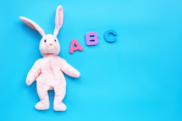 Fototapeta na wymiar Rabbit toy with english alphabet on blue background. Education concept