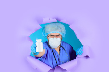 Fototapeta na wymiar Through paper. Doctor with pills. Medicine. Nurse. Package of pills. Treatment pill. Pharmaceutical drug. Bearded doctor. Doctor in mask with pills. Healthcare. Hospital and pharmacy concept.