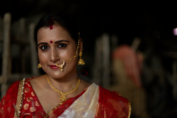 Portrait of an young and beautiful Indian Bengali brunette woman in red and white traditional...