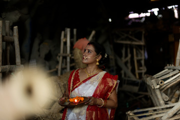 An young and beautiful Indian Bengali brunette woman in red white traditional ethnic sari holding a...