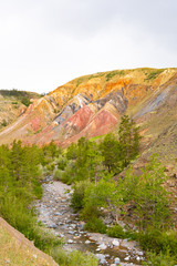 Colored hills in mountain valley. Dry sandy red hills on hot summer day. Drought, climate change. Soil erosion in ravines