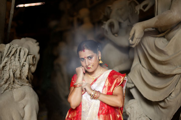 Portrait of an young and beautiful Indian Bengali brunette woman in red and white traditional...