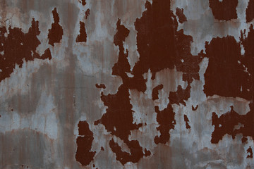 Old weathered painted wall background texture. Red dirty peeled plaster wall with falling off flakes of paint.Peeling paint on a metal surface.Cracked paint damaged concrete rough texture.