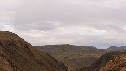gentle red hills, journey through mountain valley, pastures for animals, soil erosion in arid steppe