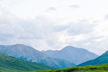 rocky ridge on horizon in mountain valley, green slopes of gentle hills, beauty of nature for relaxation and meditation