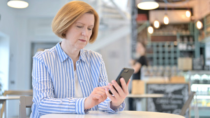 Smartphone use by Creative Old Woman in Cafe