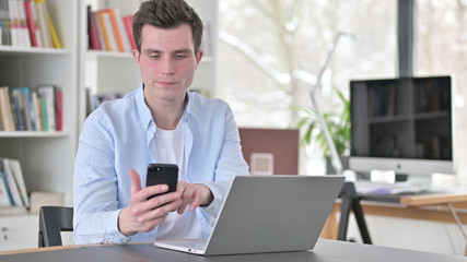 Fototapeta na wymiar Young Man Using Smartphone at Work