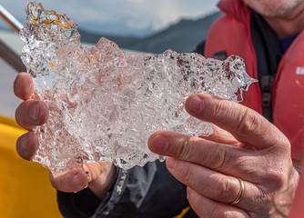 hands holding ancient ice crystal on Tasman Lake, Mount Cook