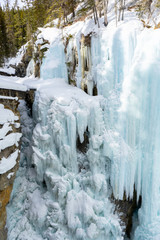 Fototapeta na wymiar Frozen upper falls at Johnston Canyon Trail in winter, icy waterfalls landscape view. Banff National Park, Alberta, Canada