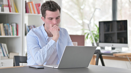 Young Man Thinking and Working on Laptop