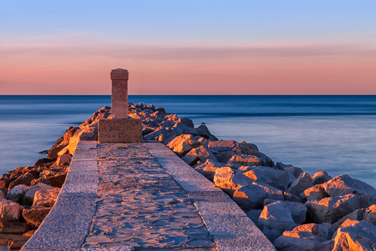 Alba sul mare con obelisco e rocce. Laguna di Grado provincia di gorizia. Italia. Isola del sole.