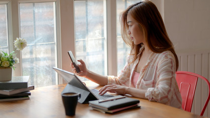 Cropped shot of college girl working on her assignment with tablet, smartphone and stationery