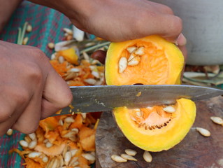 Closeup on young housewife cutting pumpkin.