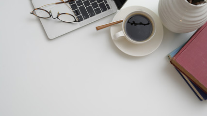 Top view of workplace with laptop, coffee cup, books and copy space