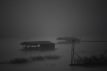 mystery scene of raft house in a wetland. indigenous people living in swamp bog. fog covered and...
