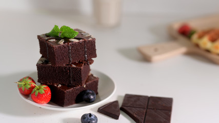 Close up view of stack chocolate brownies on white plate with mint leaf on top
