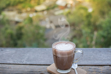 Coffee cup on the wooden table with nature landscape background.