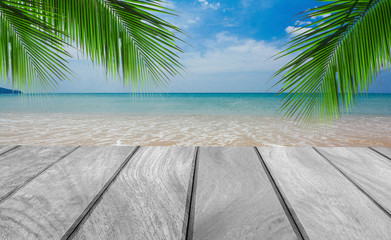 Wood table top on the beach with tropical palm leaf and blue sky, Summer vacation concept