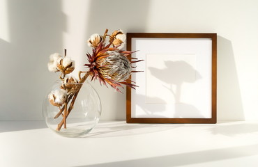 photo frame mock up, dry exotic flowers in a vase on the table and shadows. interious design. copy...