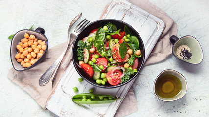 Vegan salad with cucumber, tomato, spinach, lettuce, onion, green pea and chickpea