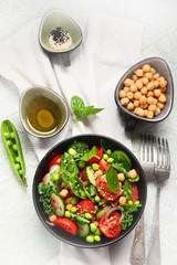 Vegan salad with cucumber, tomato, spinach, lettuce, onion, green pea and chickpea