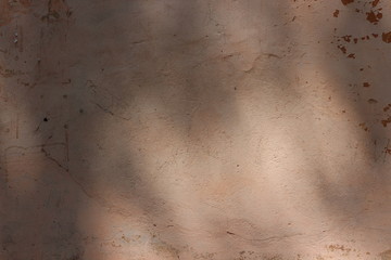 pale brown plastered weathered wall with shadows on it