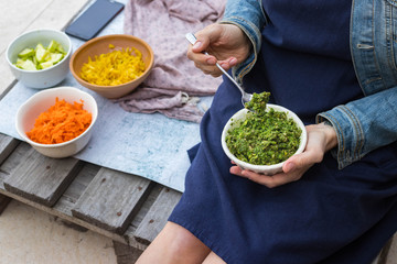 Green pesto dip paste with walnuts, seeds, nuts, parsley, basil, dill, mint, cilantro herbs and oil. Woman holds pesto in hands, eat it.