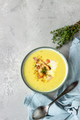 Thick milky chowder soup with seafood served with sour cream, thyme and pepper. Light grey stone background. Top view.