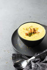 Bowl with thick clam chowder, decorated with seafood, thyme and pepper. Grey stone background. 