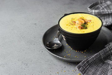 Bowl with thick clam chowder, decorated with seafood, thyme and pepper. Grey stone background. 