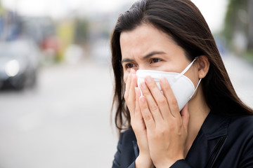 Close up of a businesswoman in a suit wearing Protective face mask and cough, get ready for Coronavirus and pm 2.5 fighting against beside road in background.