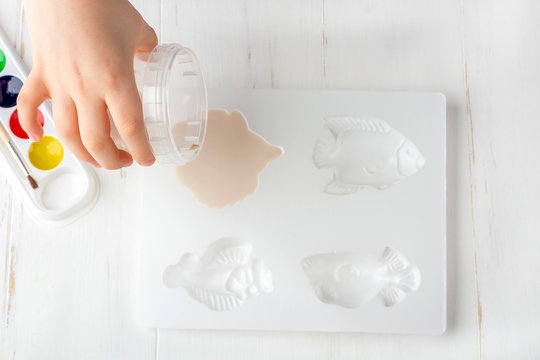 Step by step instruction: how to make plaster molding (figures). Concept of DIY and children's creativity. Making bas-reliefs on magnets. Step 7 pour gypsum solution into a plastic mold