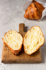 Croissant cut in a half for a sandwich on wooden cutting board. Homemade fresh golden croissant. 