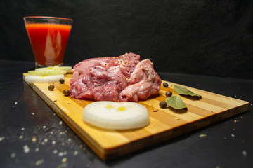 Fresh meat on a cutting board, a glass of tomato juice