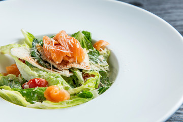 Caesar salad with fish in a plate on a table of gingerbread tree. Close-up.
