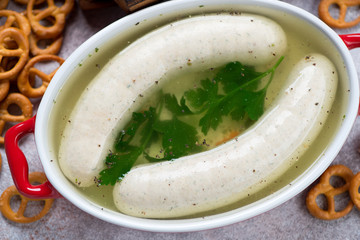 Close-up of weisswurst or white sausages served in bouillon with pretzels, view from above