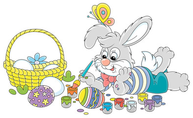 Happy little grey bunny painting beautiful ornate Easter eggs with bright and colorful paints and an art paintbrush, vector cartoon illustration on a white background