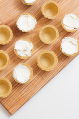 Tartlets with custard or cottage cheese. Empty tartlets or pie on a white table. Food lay flat. The view from the top. The concept of preparing food for the holiday table.