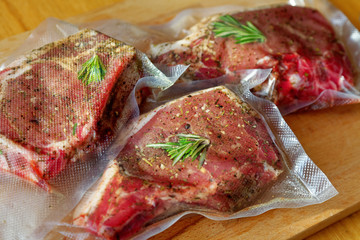 Close up of a vacuum-packed pork steak on a wooden cutting board