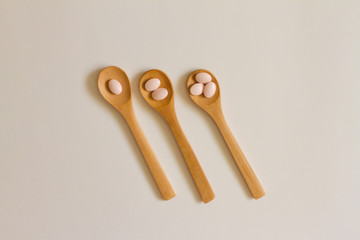 Assorted pharmaceutical medicine. Dosage. Tablets and capsules on a wooden spoon on a white background. Concept of medicine. Alternative homeopathy. Flatley. The view from the top.