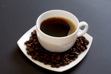 coffee beans in a bag with a white Cup of fresh coffee on a black background. space for text, top view.