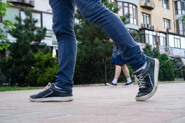Guy's legs in running in blue pants and blue summer shoes. In the background is a girl in a blue summer dress and low-heeled shoes. The story of how everyone hurries about their business.