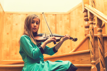 Girl with a violin on a wooden staircase. toned