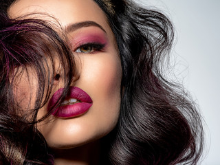 Portrait of beautiful young woman with bright maroon makeup. Beautiful brunette with bright cherry...