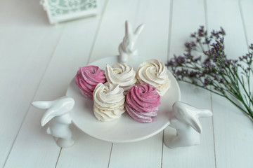 beautiful delicate marshmallows lie on a beautiful plate held by porcelain hares